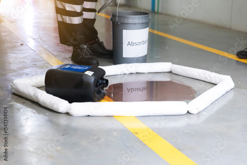 Industrial spill containment barrier kit on warehouse concrete floor with yellow safety lines