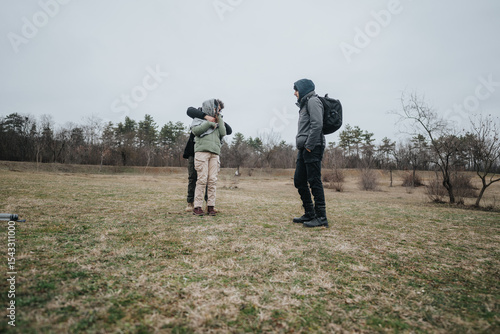 Obraz na plátně Three people interact in a scenic outdoor field landscape, embraced in cordiality and warmth