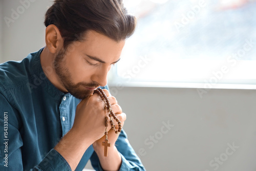 Tableau sur toile Man with rosary beads praying at home