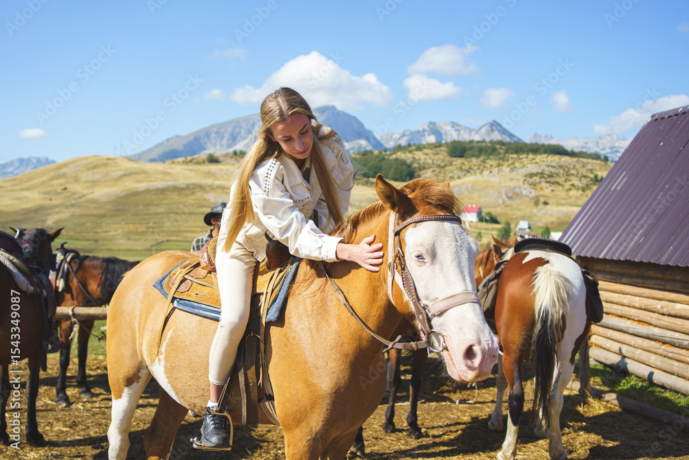 Young woman sitting on horse and hugging it at a mountain ranch in Montenegro on a sunny day. Young woman sitting on horse and hugging it at a mountain ranch in Montenegro on a sunny day.