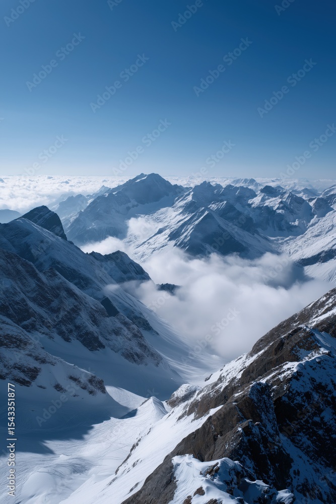 Fototapeta premium Snow-capped mountain peaks and vast cloudscape under clear blue sky