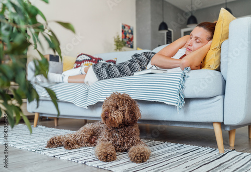Obraz na płótnie Maltipoo dog lying on carpet while middle aged female sleeping relaxing on comfo