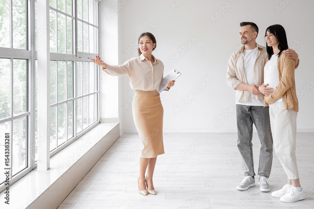 Fototapeta premium Female Asian real estate agent showing new house to pregnant couple