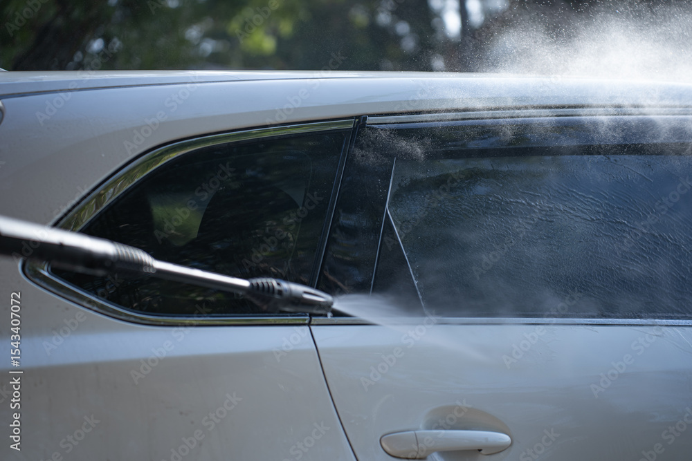 Fototapeta premium washing a dirty car and wheels with water and a pressure washer