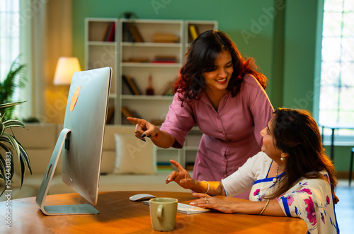 Photography Indian mother and daughter enjoy using computer together at home while shopping