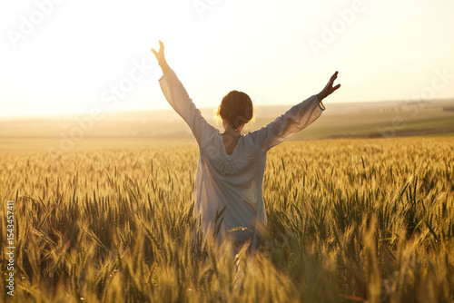 Woman with outstretched arms in a wheat field.