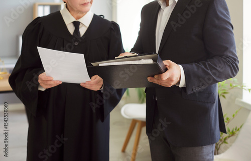 Fotografie Judge woman in professional outfit black robe standing engaged in reviewing docu