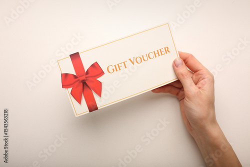 Top view of woman holding gift voucher lettering on white background