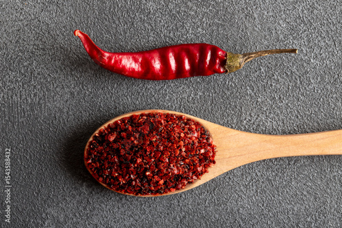 Red pepper flakes.Red chili peppers in wooden spoon on gray background.Dried chili peppers
