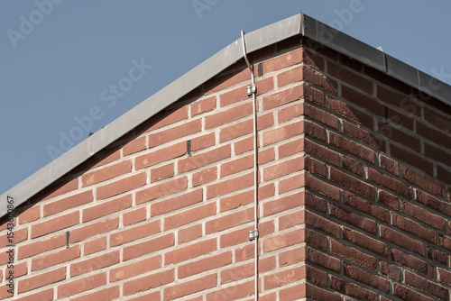 Bild auf Leinwand Lightning rod cable running down brick wall of building