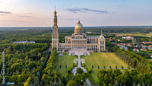 Bild auf Leinwand Aerial view of the Basilica in Licheń Stary at sunset, a monumental church with a tall tower and dome, surrounded by gardens and greenery