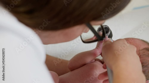 A doctor examining a newborn baby in a clinic setting. The image could be related to neonatal care, potentially involving ultraviolet light.