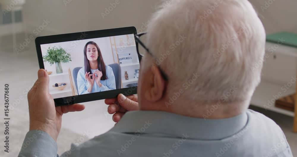 Elderly man talking to family via an online video call on a tablet computer at home. Importance of online communication for seniors to stay connected through internet with loved ones. Elderly man talking to family via an online video call on a tablet computer at home. Importance of online communication for seniors to stay connected through internet with loved ones.