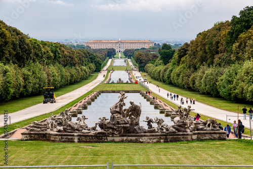 Panoramic view of the Royal Palace of Caserta and its long central water axis, captured from the upper fountain with statues in the foreground