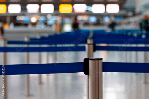 Close-up of a metallic barrier pole with blue retractable belts with others in behind located in an airport terminal