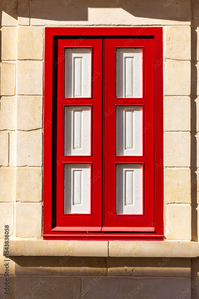 Fototapeta premium Bright red and white window shutters in stone building.