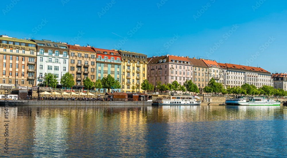 Obraz premium A view from the Vltava river towards colourful buildings on the east bank in Prague in springtime