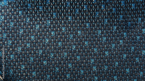 Close-up of a dark blue fabric with a subtle repeating geometric pattern of abstract light-colored shapes. Ideal for garment design, apparel accents, abstract backgrounds, and fashion concepts
