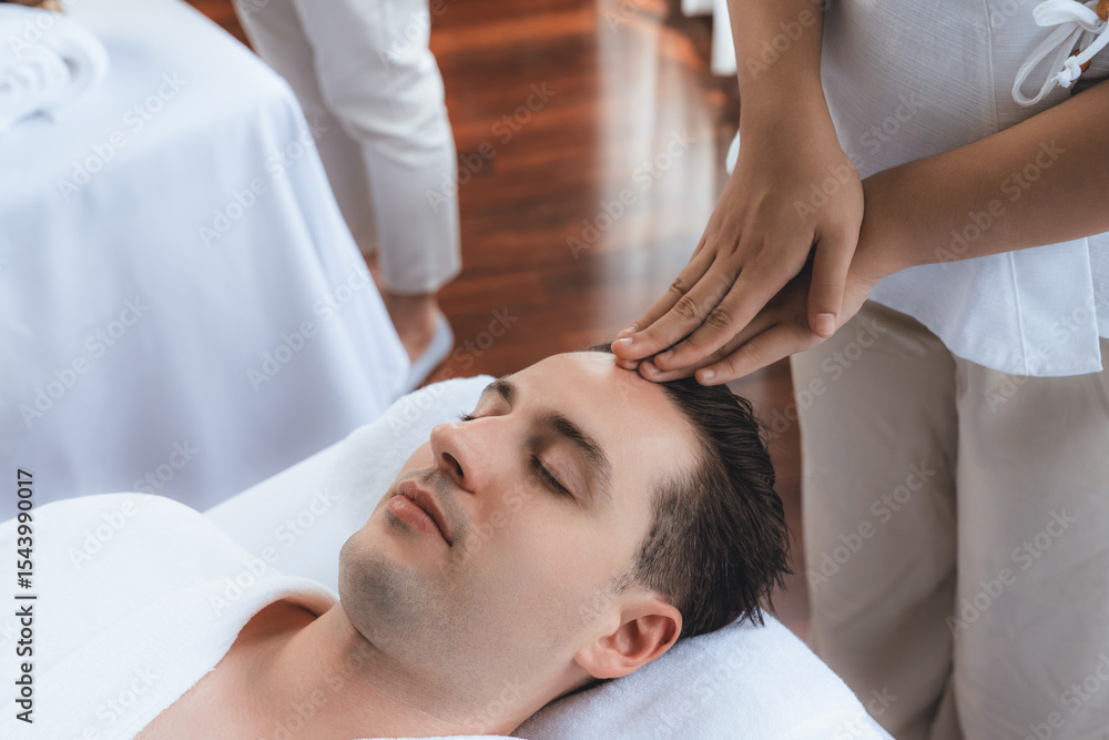 Fototapeta premium Caucasian man enjoying relaxing anti-stress head massage and pampering facial beauty skin recreation leisure in dayspa modern light ambient at luxury resort or hotel spa salon. Quiescent