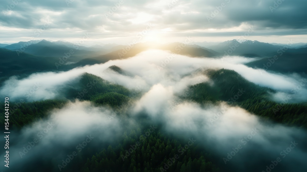 Obraz premium An aerial view of majestic mountains enveloped in mist during sunrise, showcasing the serenity and grandeur of nature in a breathtaking landscape photograph.