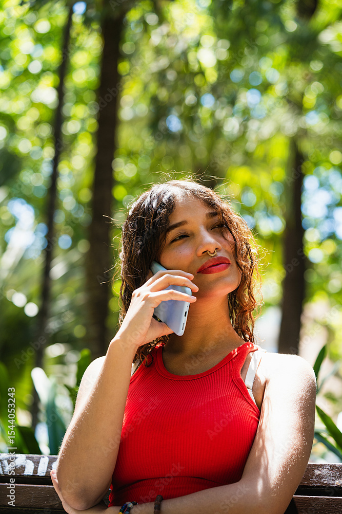 Fototapeta premium Young woman talking on mobile phone in park