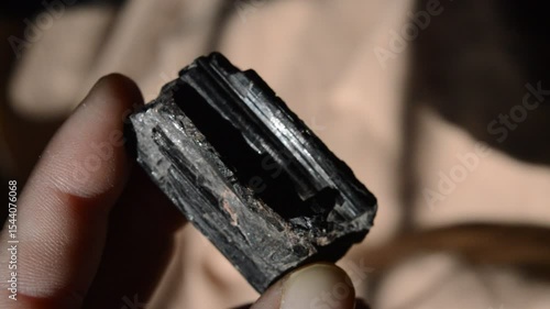 hand holding a brush Tourmaline mineral specimen at sun