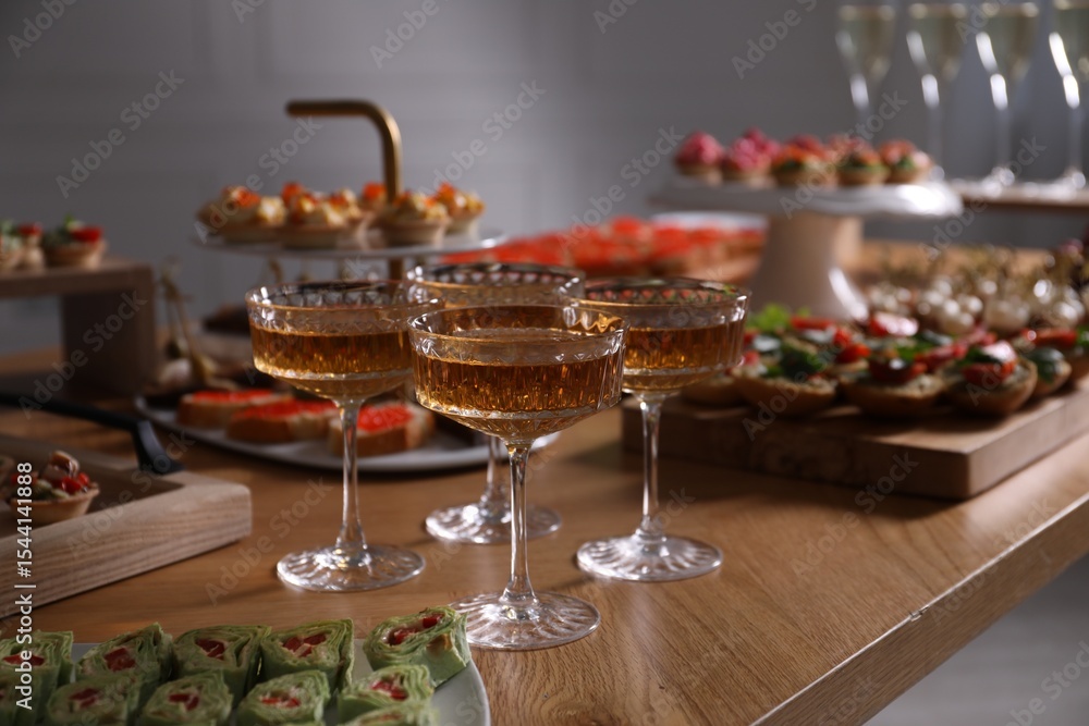 Naklejka premium Buffet menu. Glasses of sparkling wine and tasty appetizers on table, closeup