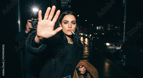 Night time photo of a female model celebrity smoking a cigarette, one hand up trying to stop paparazzi from taking a picture,  privacy, urban, city night, street lights, candid, attitude, edgy, glam