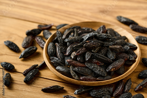 closeup pile of tonka bean in wood bowl on wooden table rustic background with copy space