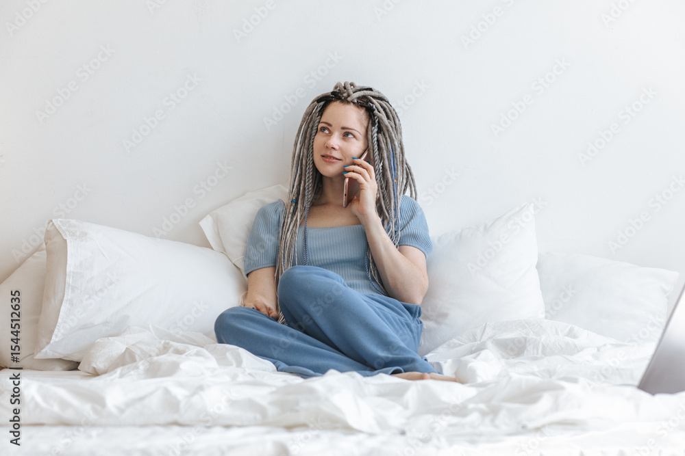 Young woman talking on phone in a white bed. Young woman talking on phone in a white bed.