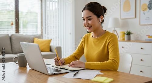 Wallpaper Mural Smiling Asian woman working from home taking notes during a video call Torontodigital.ca