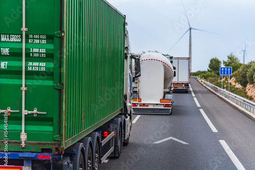 Canvas Print Several trucks in a row overtaking on a highway, merging into the left lane