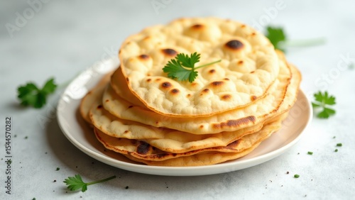 Close-up of a stack of golden-brown naan bread on a white plate, garnished with fresh parsley