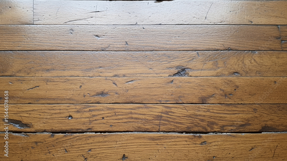 Fototapeta premium Burnished surface scratches and dusty dents expose wear marks across golden-hued boards with a rough texture.