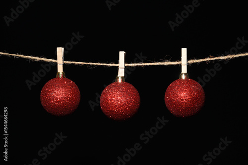 Tableau sur toile Bolas de navidad rojas colgadas con pinzas en una cuerda sobre fondo negro