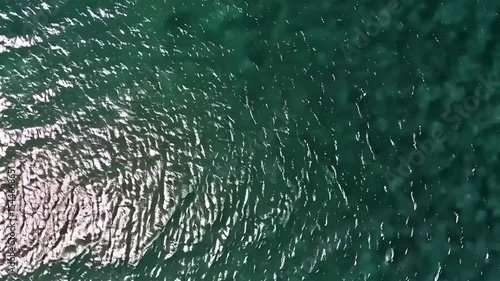 Sunlight Sparkling on Calm Ocean Waves from Above. Top-down static shot of sunlight reflecting on calm ocean waves, creating glimmering abstract patterns. Peaceful, bright, and natural