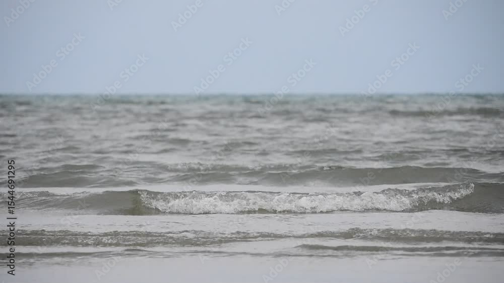 Soft wave of blue ocean on sandy beach at evening light. Background subject is soft focus and low key Soft wave of blue ocean on sandy beach at evening light. Background subject is soft focus and low key
