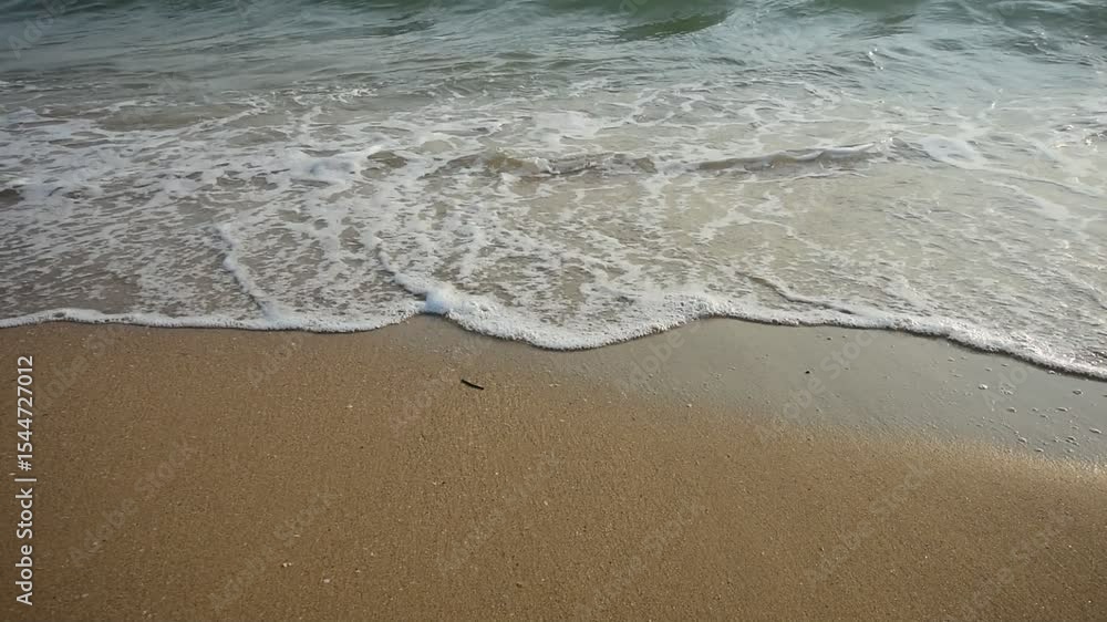 Soft wave of blue ocean on sandy beach at sunny day. Background subject is soft focus
