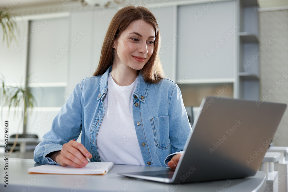Woman working on laptop at desk in public library Woman working on laptop at desk in public library