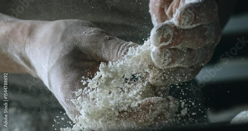 Cinematic Super slow motion close up of professional artisan baker chef sprinkles flour on raw loaf of dough while making homemade bread, pasta or pizza on rustic wooden table in traditional bakery ki