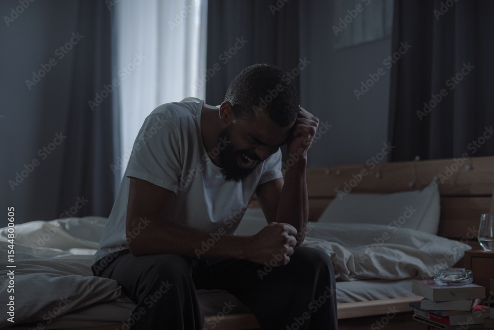 Fototapeta premium Hopeless African American man yells feeling strong stress in bedroom