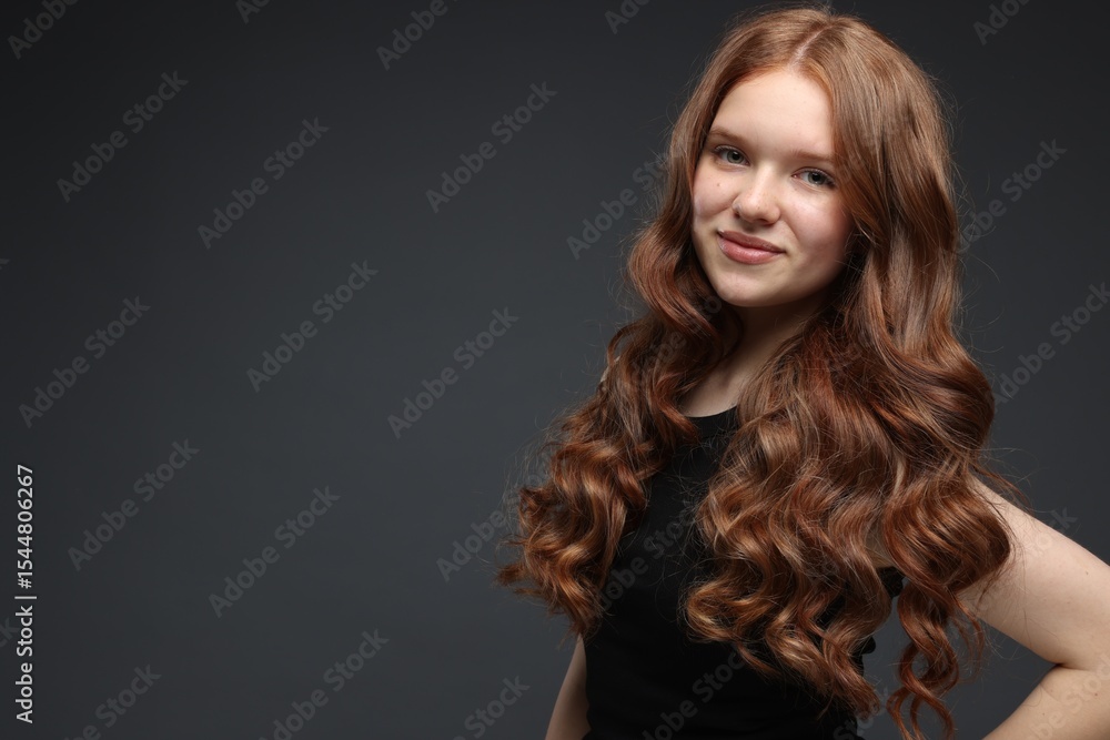 Naklejka premium Portrait of beautiful teenage girl with healthy wavy hair on dark grey background. Space for text