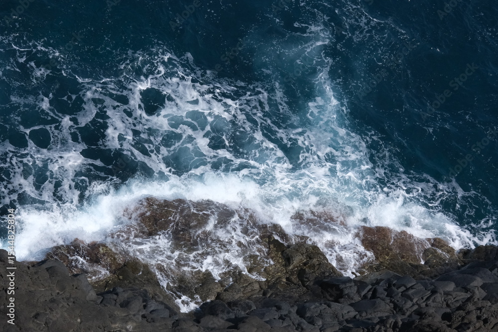 Fototapeta premium ocean waves crashing on volcanic rocks - top view