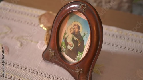 Framed icon of Saint Anthony with Child Jesus on embroidered vintage linen in traditional Mediterranean interior