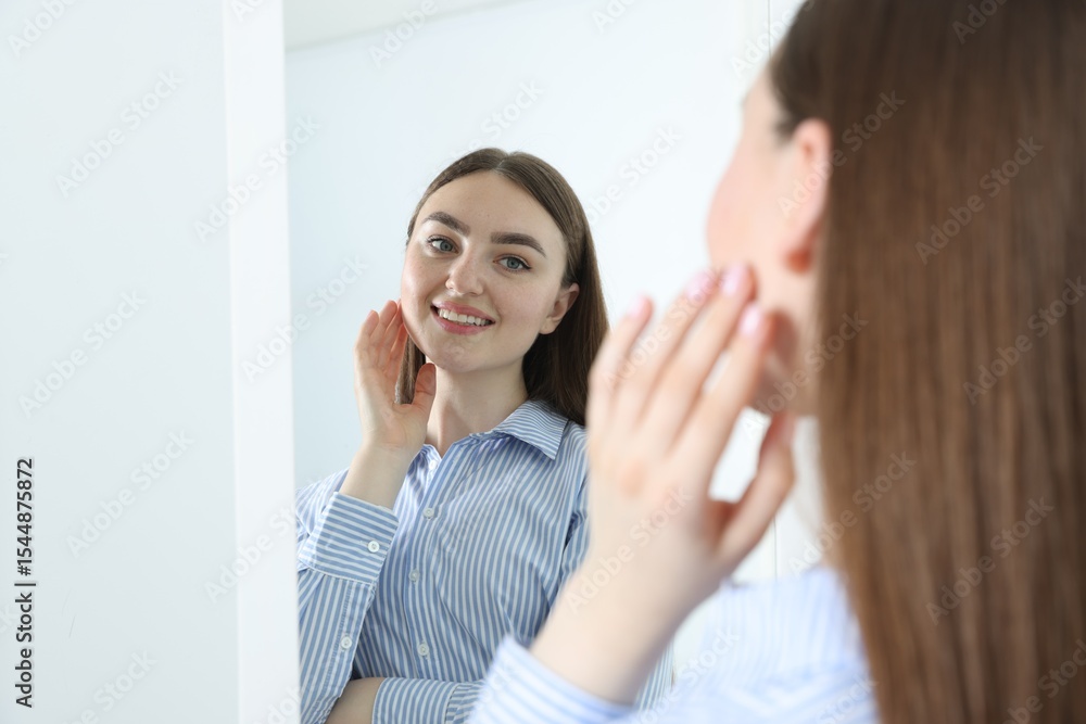 Beautiful woman looking at herself in mirror indoors Beautiful woman looking at herself in mirror indoors