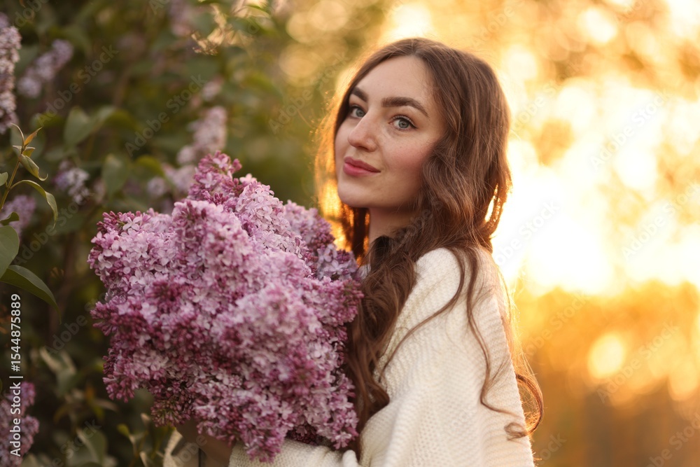 Fototapeta premium Beautiful woman with bouquet of lilac flowers outdoors in morning