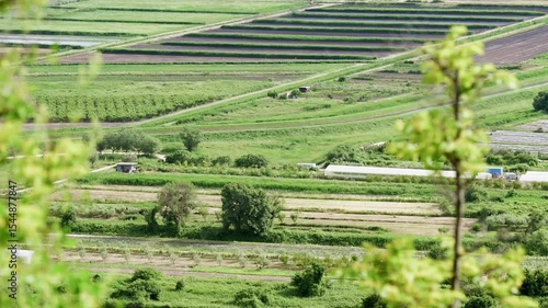 View of fertile farmland with cultivated fields, green pastures, and winding dirt roads in the Neretva Valley during springtime