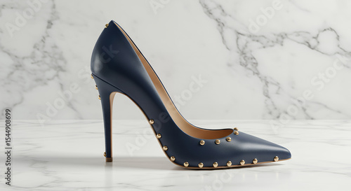 A navy blue high heel shoe with gold studs on a white marble surface