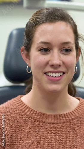 Young caucasian woman, mid-20s, in a brown knit sweater, undergoes an eye exam. Her expression transitions to a soft smile as a phoropter adjusts before her eyes. Soft clinical lighting & subtle