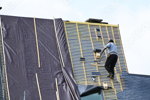 ouvrier couvreur sur un toit d'habiation en cours de rénovation
